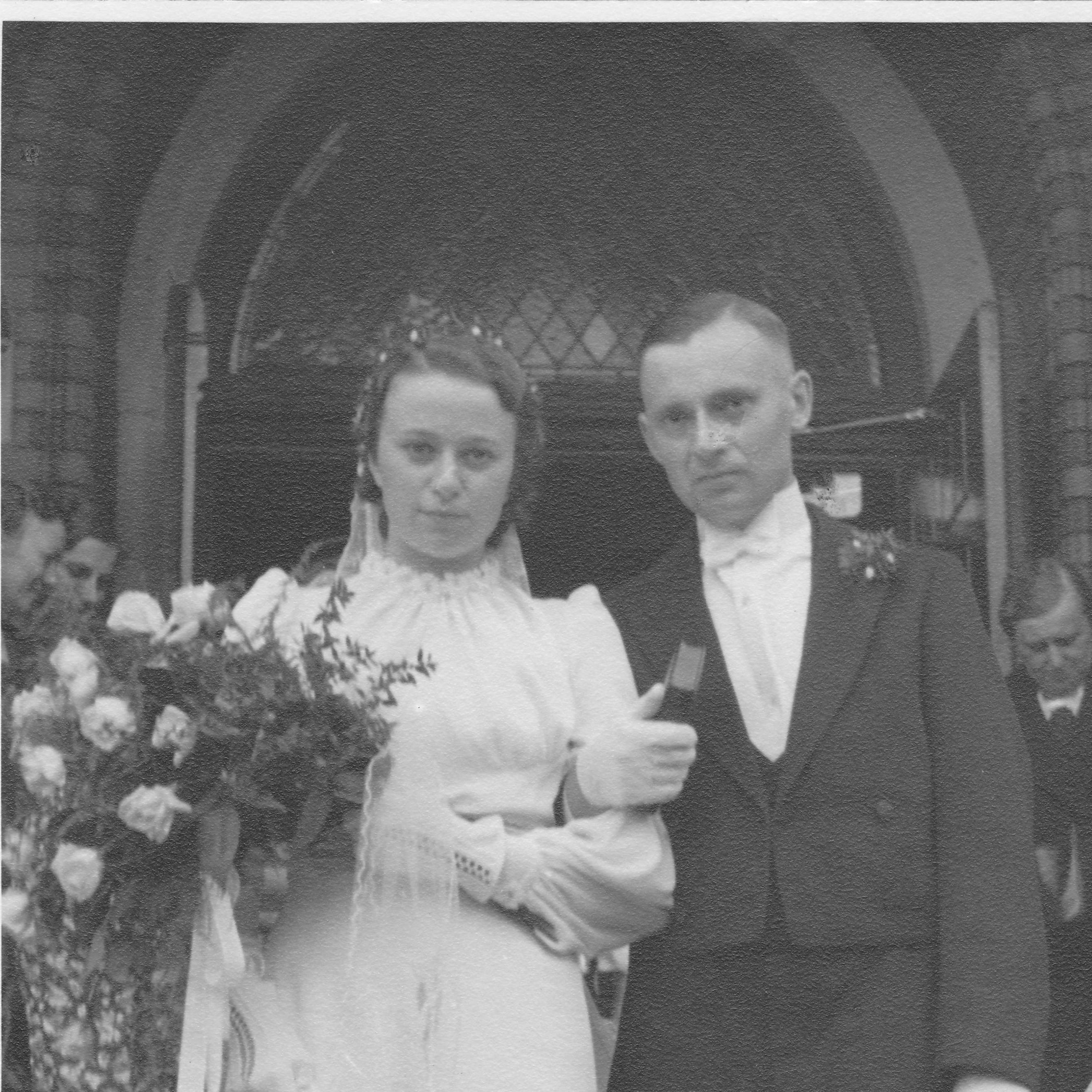Fotografie des Brautpaars Nordhoff am Tag ihrer Hochzeit vor dem Portal der Kirche. 