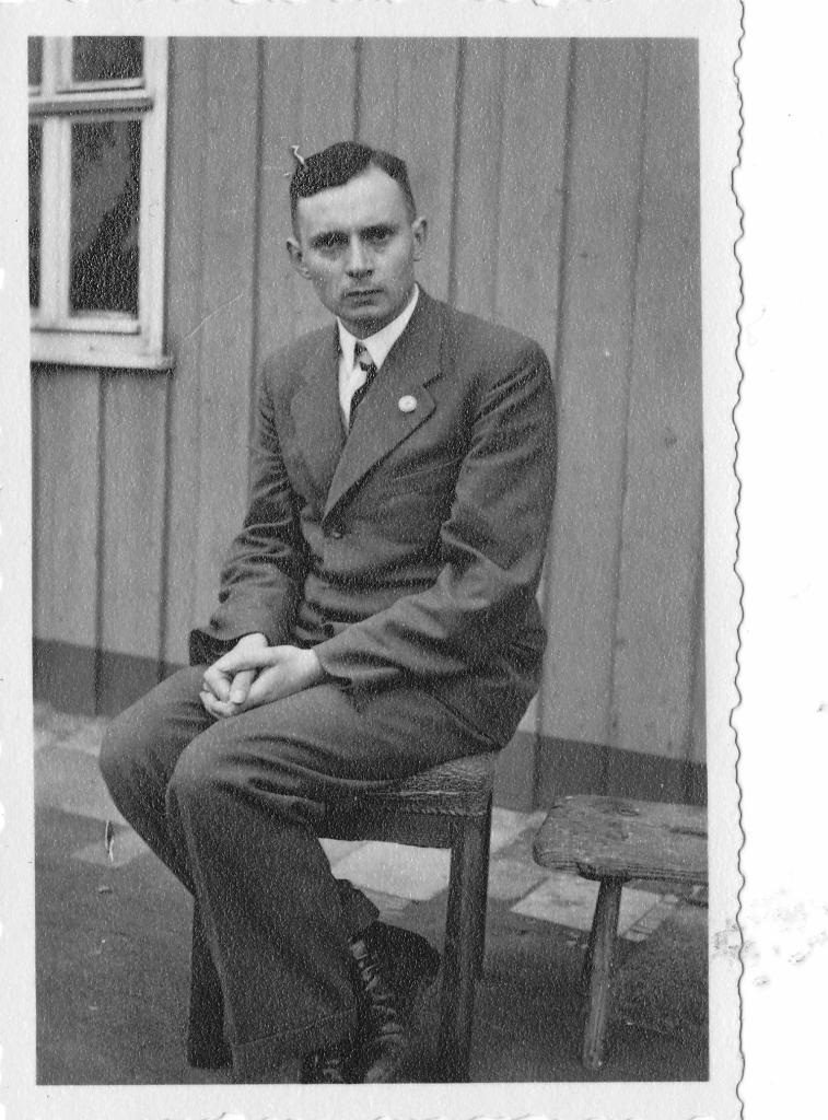 Roland Nordhoff, der vor einem Holzhaus auf einem Stuhl sitzt. 