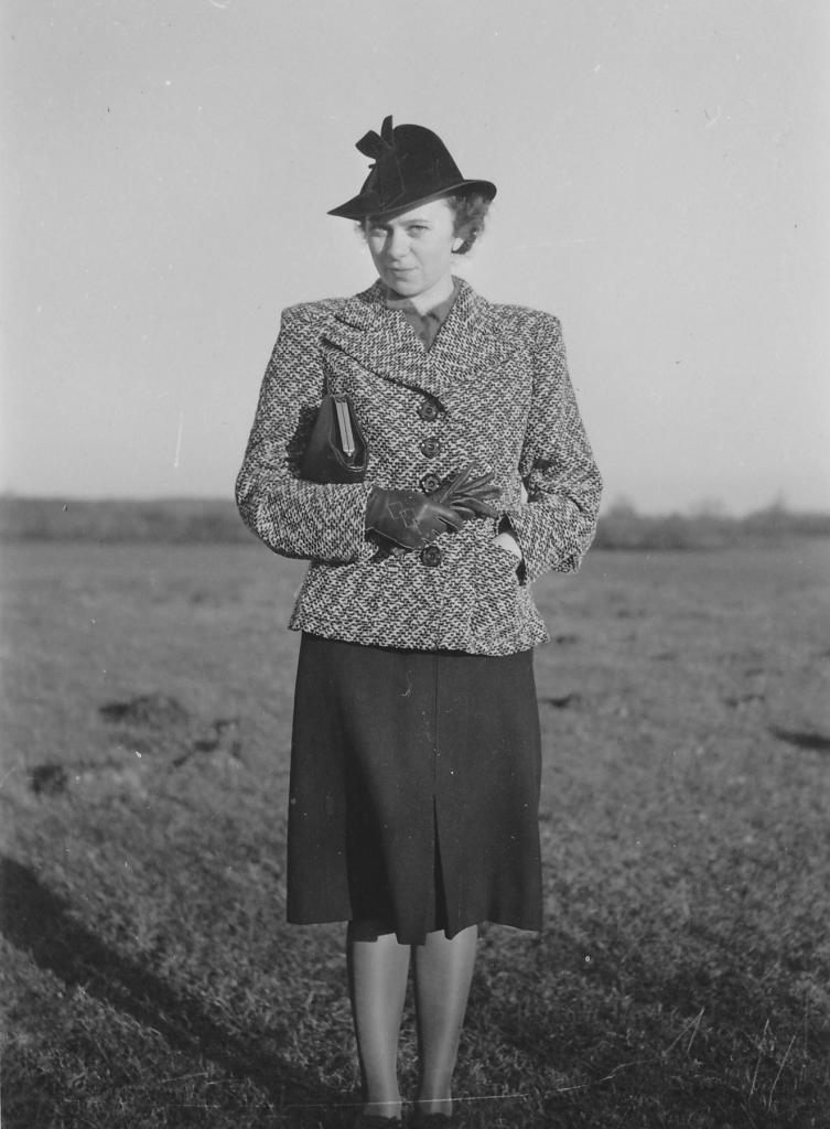 Hilde Nordhoff auf einer Wiese, warm gekleidet mit Handschuhen und Hut.