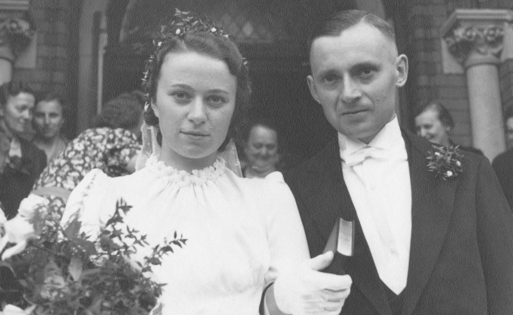 Halbnahe Aufnahme des Brautpaares Nordhoff am Tag ihrer Hochzeit vor dem Portal zur Kirche. 