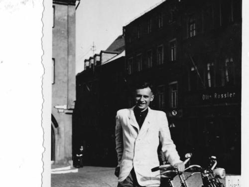 Halbnahe Aufnahme von Roland Nordhoff, der an ein Fahrrad lehnt. Im Hintergrund eine Häuserzeile.