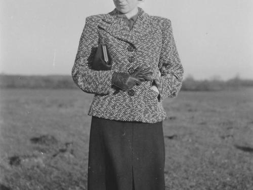 Hilde Nordhoff auf einer Wiese, warm gekleidet mit Handschuhen und Hut.