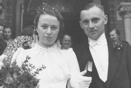 Halbnahe Aufnahme des Brautpaares Nordhoff am Tag ihrer Hochzeit vor dem Portal zur Kirche. 